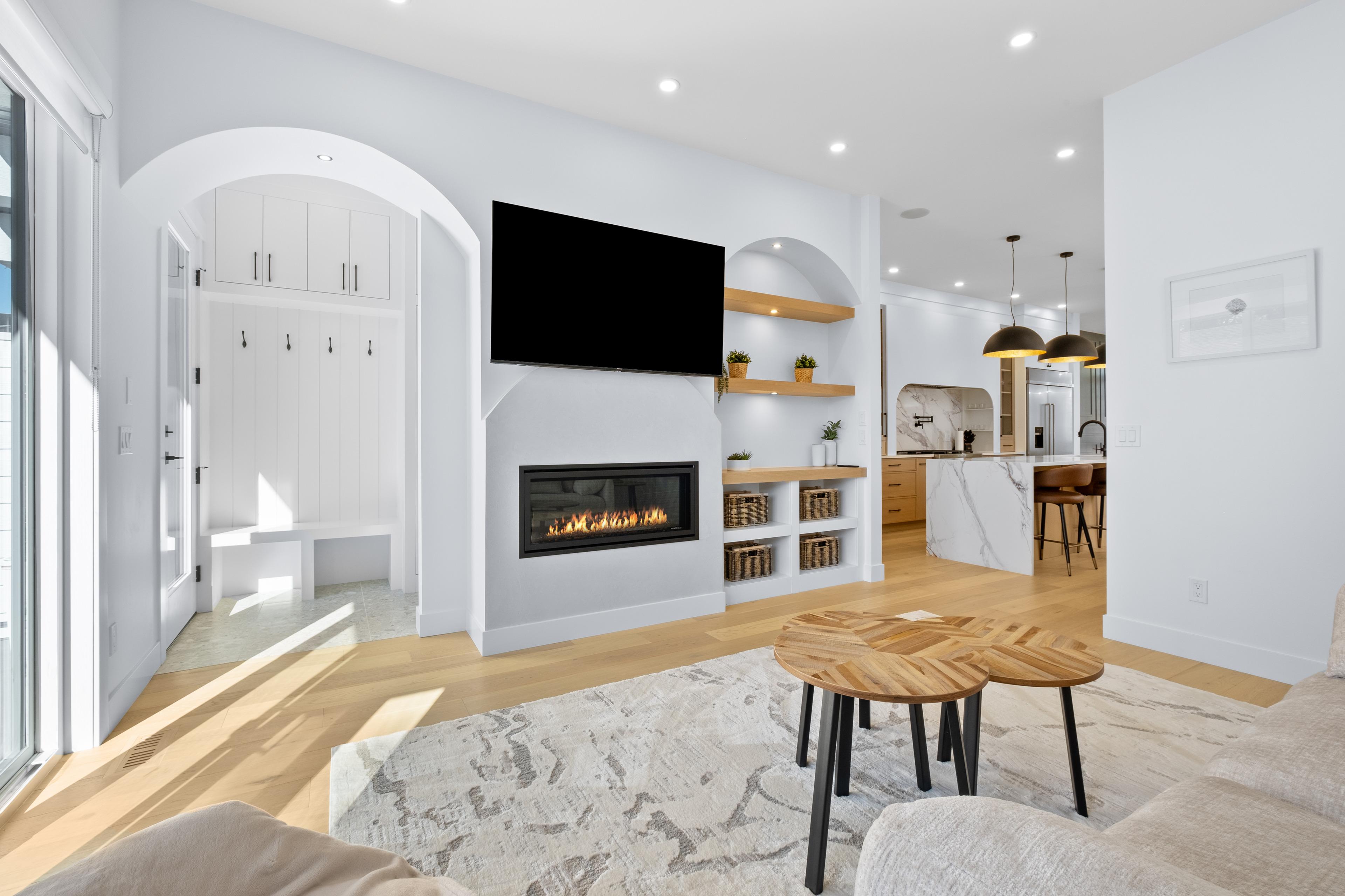 Bright living room with a fireplace, arched mudroom nook and open kitchen