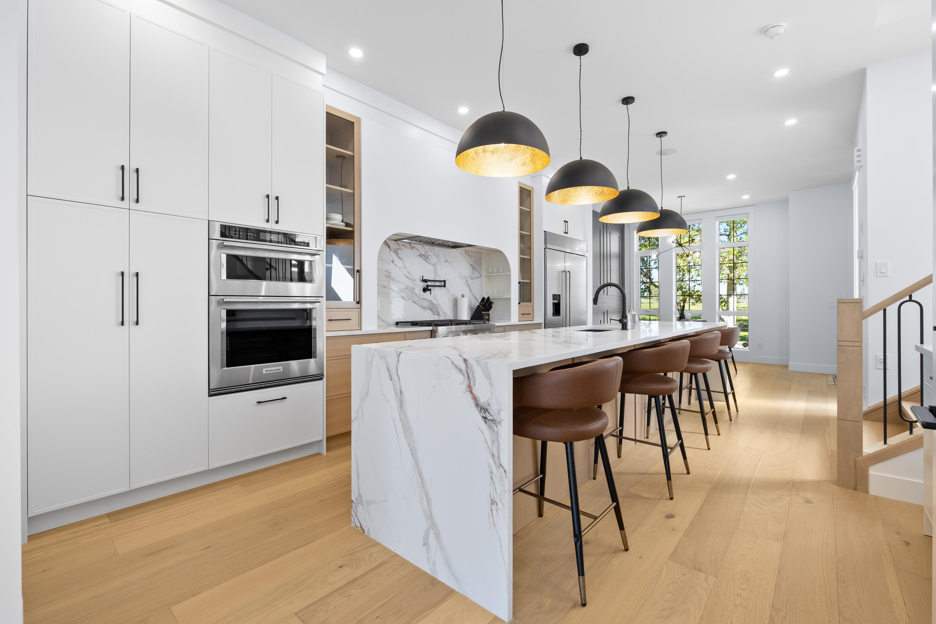 White kitchen with a marble waterfall island and black pendant lights