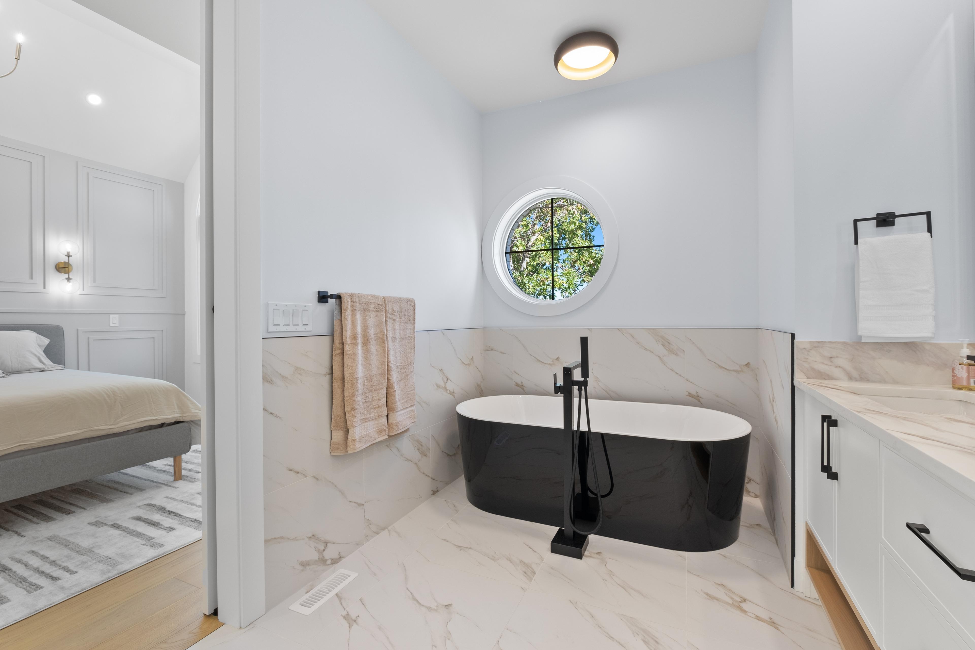 Ensuite bathroom with a freestanding black tub and marble tile