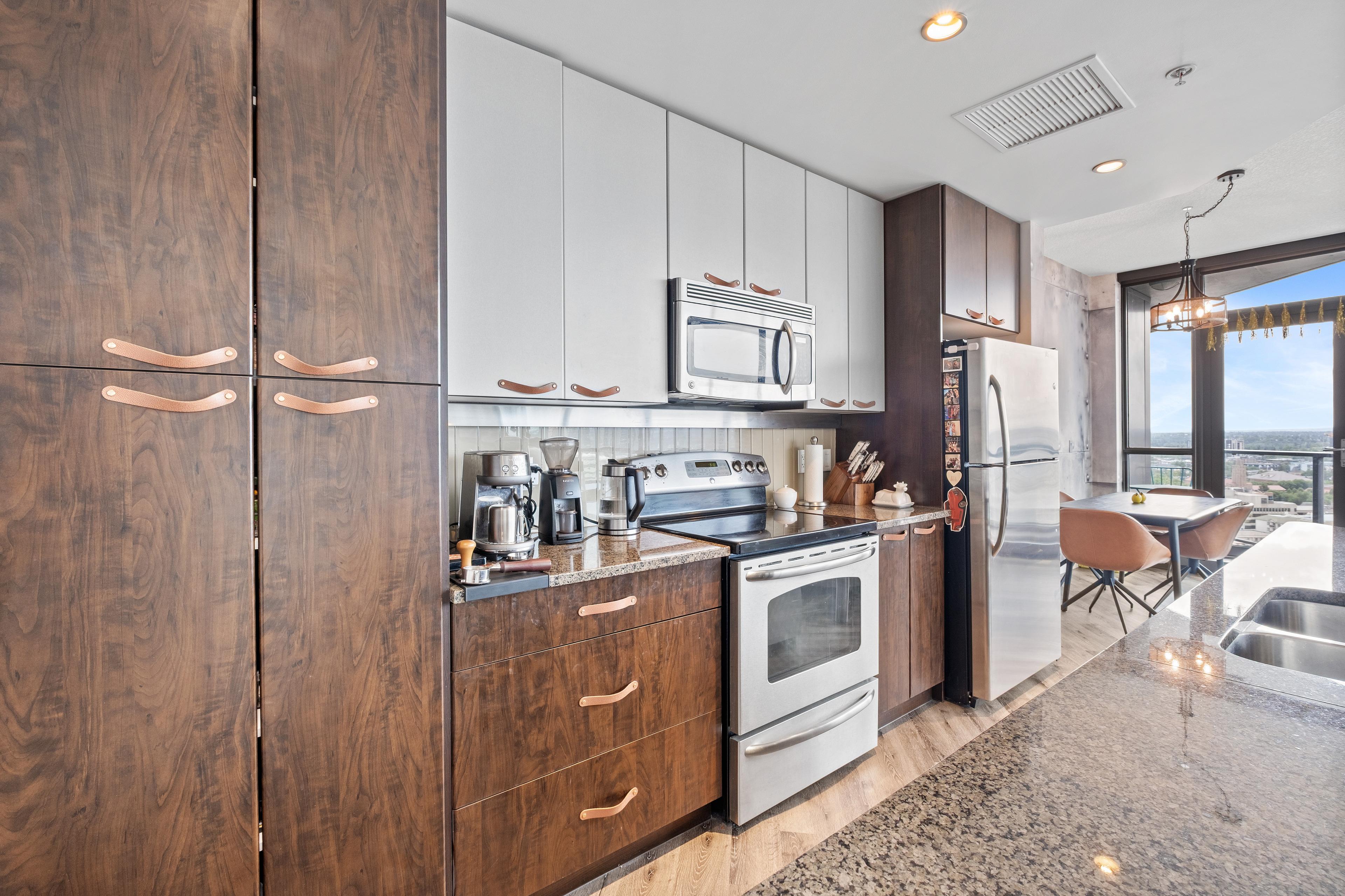 Condo kitchen with dark wood cabinets, stainless appliances and a dining nook